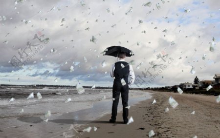 沙滩打着雨伞遮挡金钱雨的商务人物图片