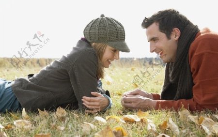 秋天趴在草地上聊天的情侣图片