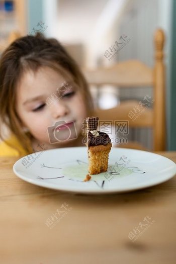 女孩在白色陶瓷圆盘看着蛋糕