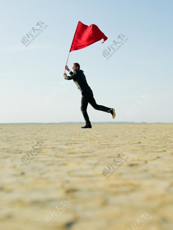 挑着红旗在奔跑的外国商务男士图片