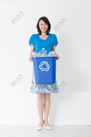 端着一桶塑料瓶微笑的女人图片