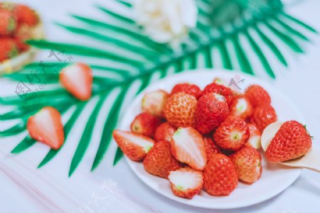 一盘草莓和勺子里的新鲜草莓