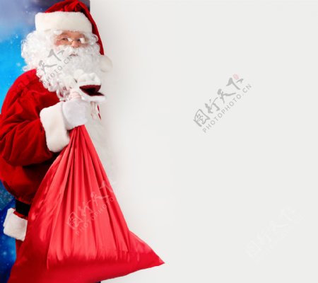 空白广告牌旁边手拿礼品袋的圣诞老人图片