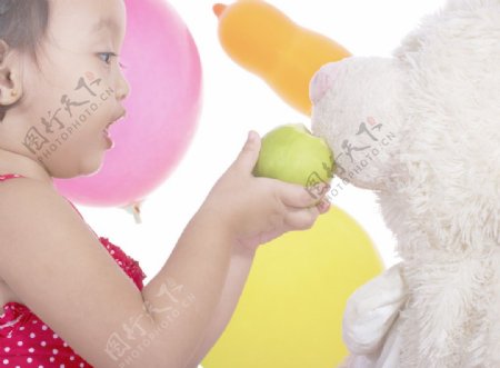 孩子喂她的泰迪熊一个苹果