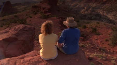 夫妇坐在一个红色的悬崖和欣赏观国会礁国家公园的股票视频视频免费下载