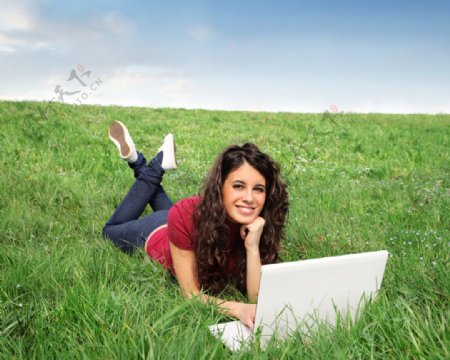 趴在草地上笔记本上网聊天的美女图片