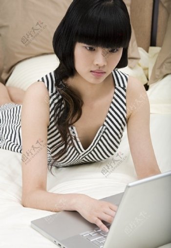 趴在床上笔记本电脑上网聊天的美女图片