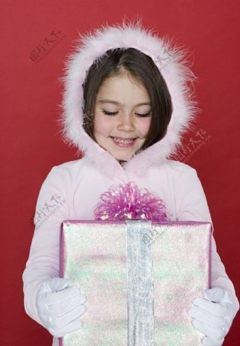 穿羽绒服抱着礼盒的甜蜜小女孩图片