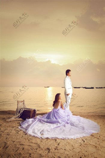 沙滩上望着远方的情侣摄影图片