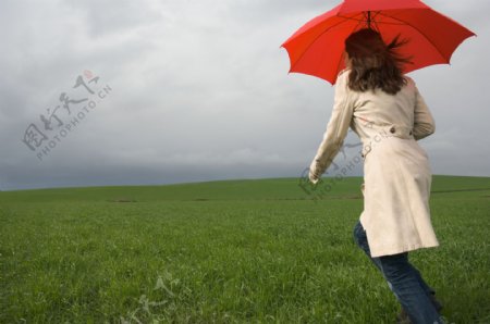 撑着伞在草地上奔跑的女人图片