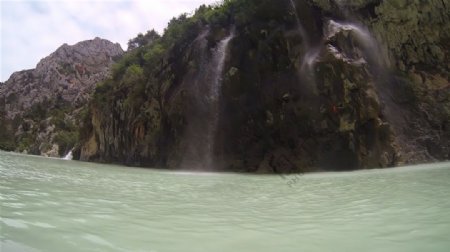 壮丽山河景色高山围绕流水瀑布冲击河流上行驶高清视频实拍