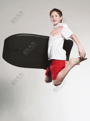 抱着冲浪板跳跃的外国男孩图片