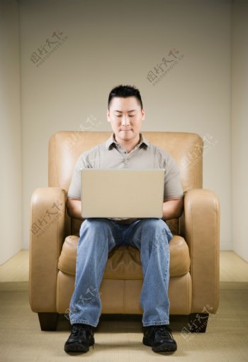 坐在沙发上玩电脑的男人图片