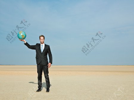 蓝天下举起地球仪模型的男人图片