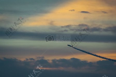 飞行航空器在白云在与橙天日落