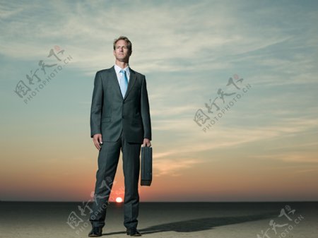 在沙漠中提着皮箱的商业男人图片