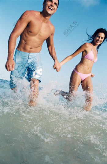 手牵手走在海水中的情侣图片