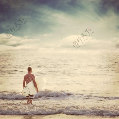 海水中拿着冲浪板的男人图片