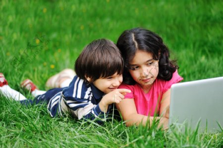 趴草地上玩电脑的儿童图片