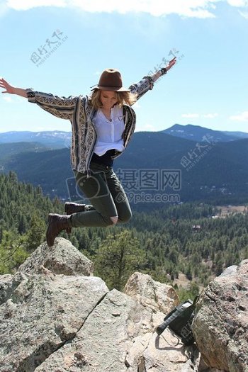 女孩在山石上高兴跳跃着