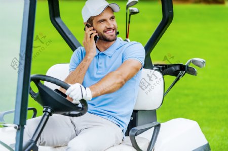 高尔夫球车上打电话的男人