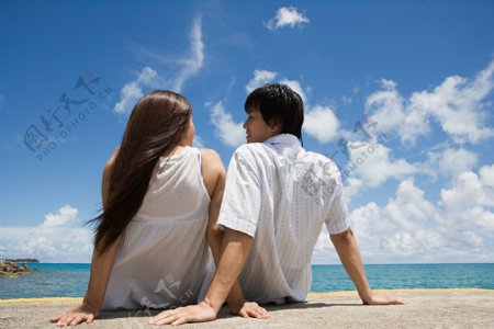 坐在海边依偎在一起谈话的情侣图片图片
