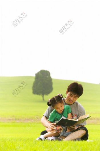 草地上看书的父女图片