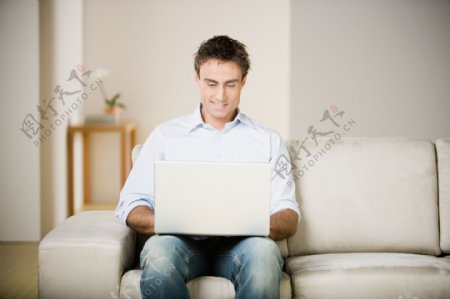 坐在沙发上玩电脑的男人图片