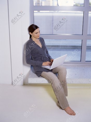 坐在窗台上玩电脑的女人图片