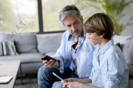 用手机玩游戏的男孩和父亲图片