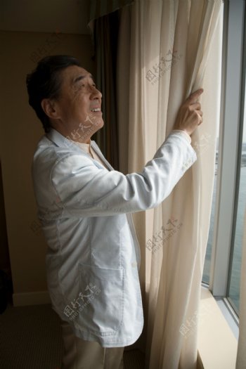 手拉窗帘的中年男人图片